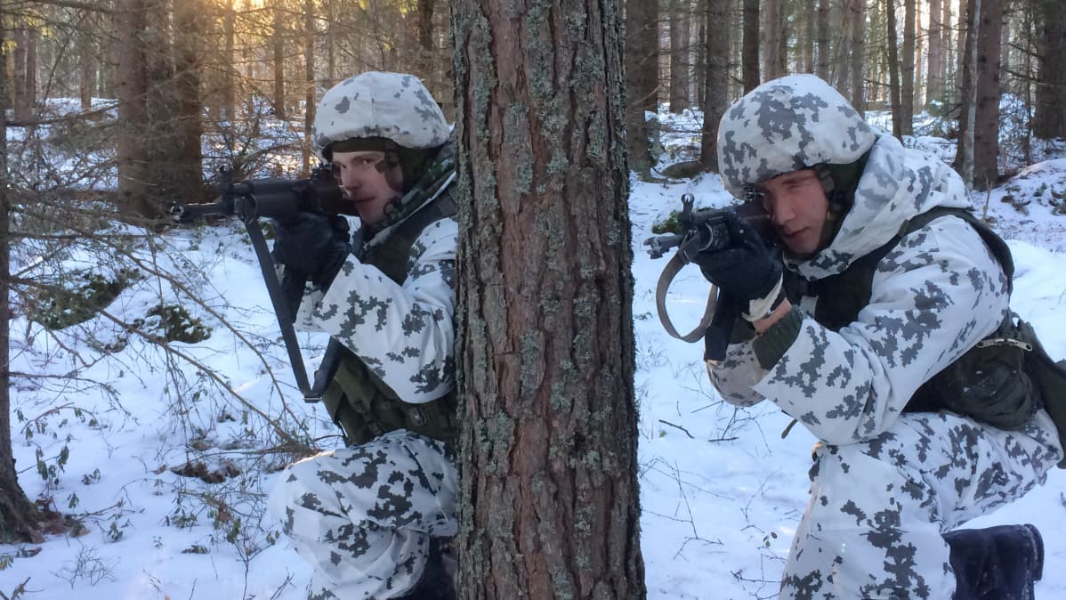 Kaksi alokasta lumipuvuissa rynnäkkökivääreiden kanssa metsässä asemissa.