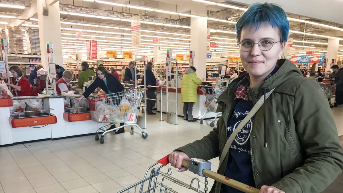 nainen ostoskärryjen kanssa marketissa