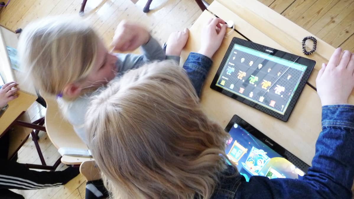 Koululaisia tablettitietokoneen äärellä luokkahuoneessa.