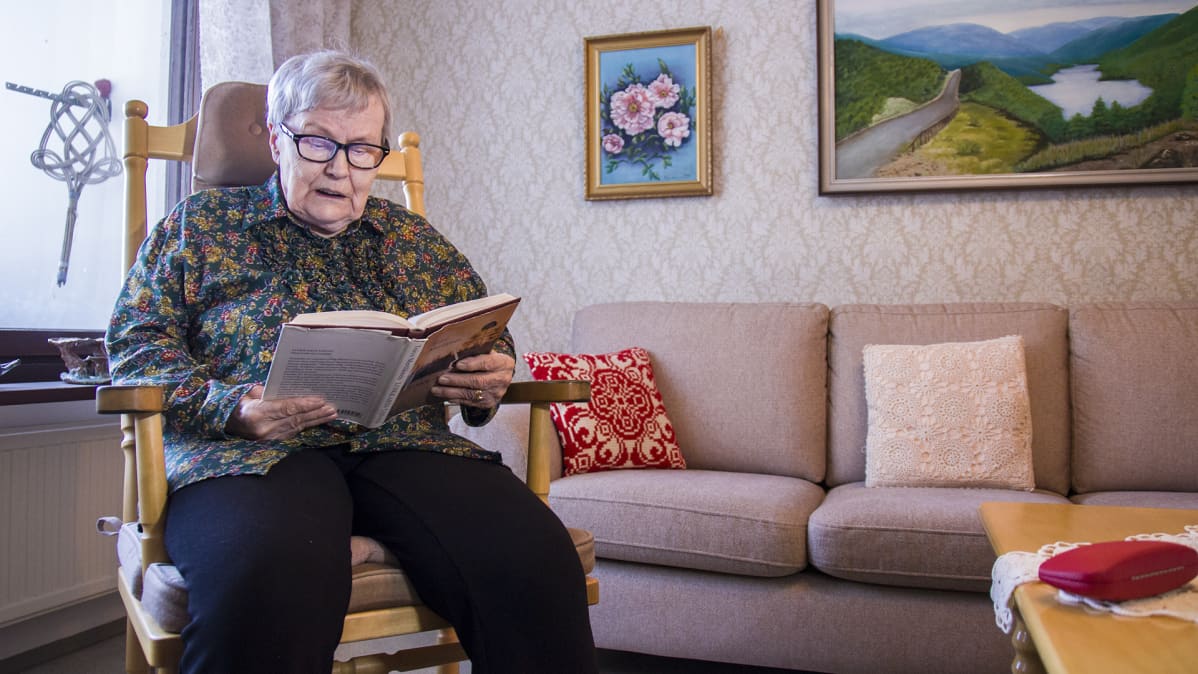 Leila Kananen lukee kirjaa olohuoneessaan