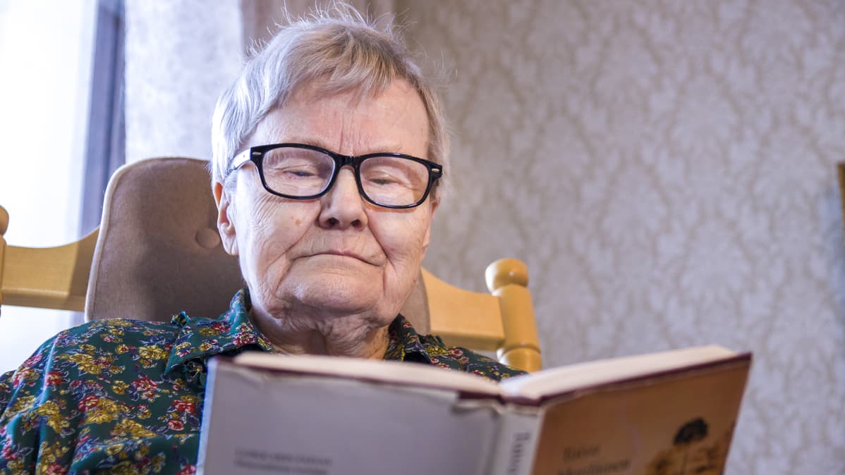 Leila Kananen istuu kiikkutuolissa lukemassa