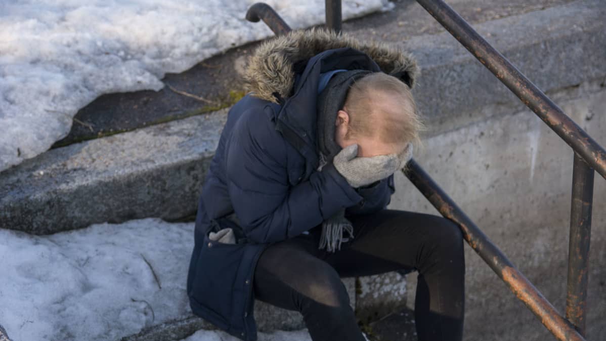 Mies istuu portailla kasvot haudattuna käsiin.