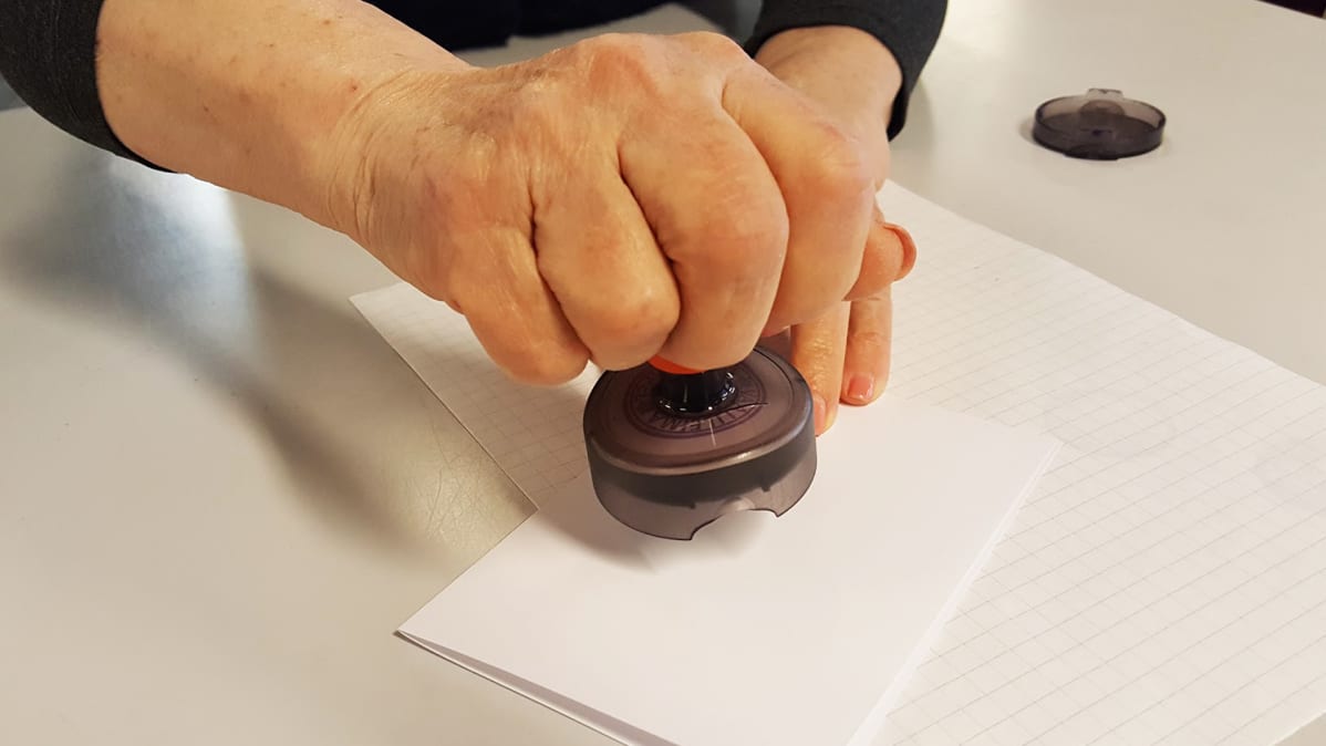 Nainen leimaa äänestyslipukkeen.