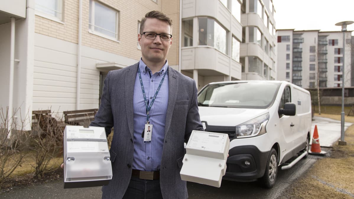 Ville Sihvolalla kädessään uusi ja vanha älysähkömittari.