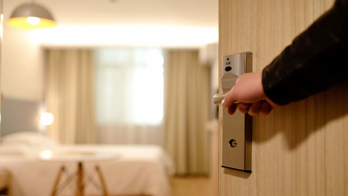 käsi hotellihuoneen ovenkahvalla