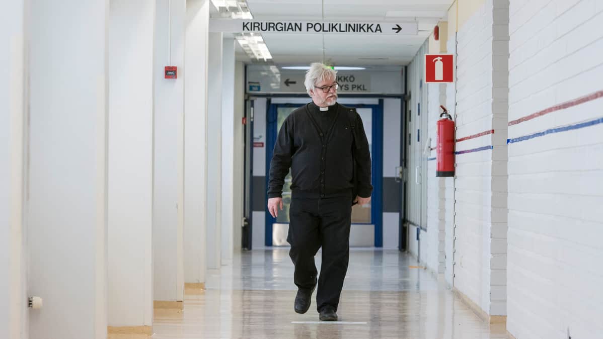Pappi kävelee sairaalan käytävällä