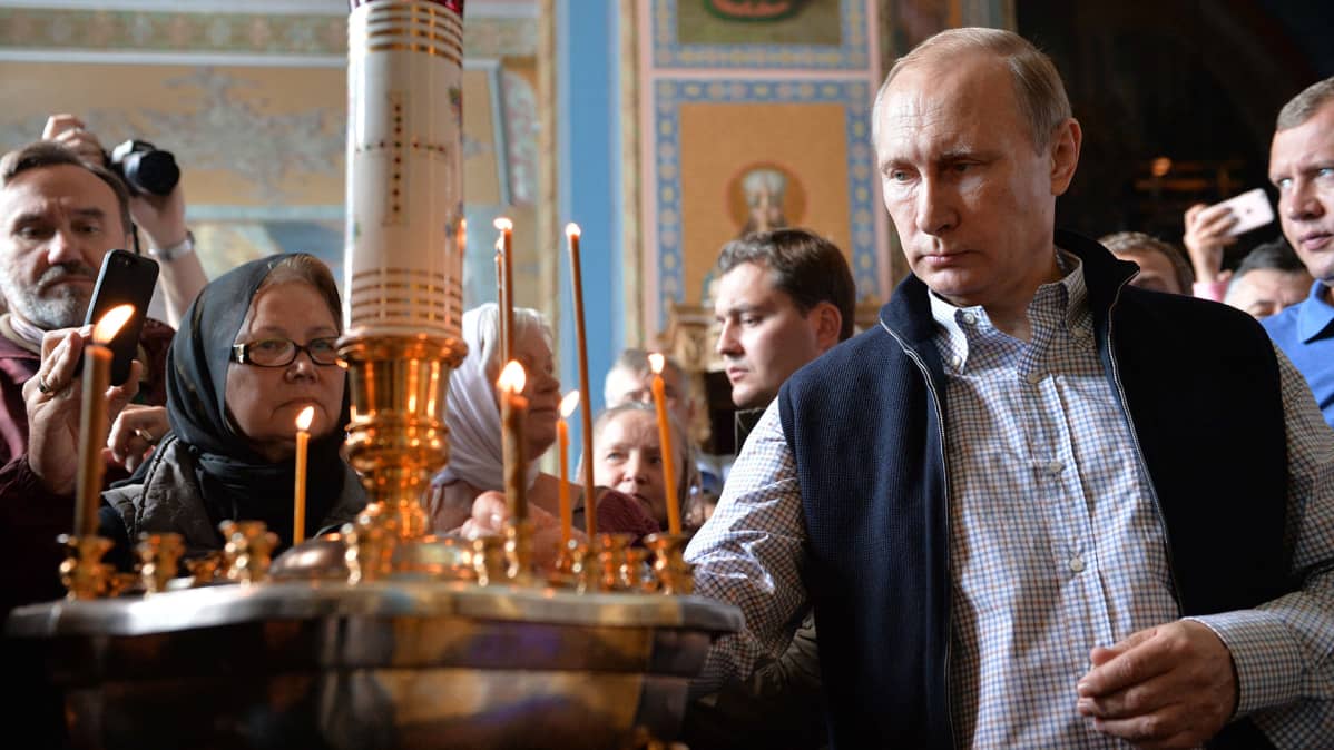 Vladimir Putin sytyttää kynttilän Valamon luostarissa.