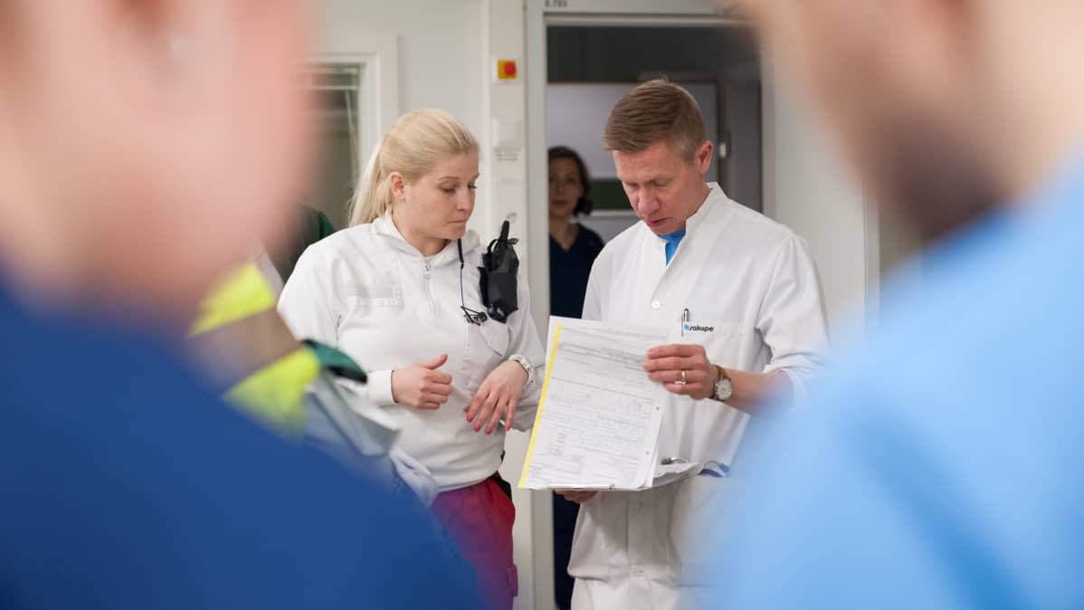 Ensihoitaja vaihtaa tietoja neurologin kanssa päivystykseen tuodusta potilaasta.