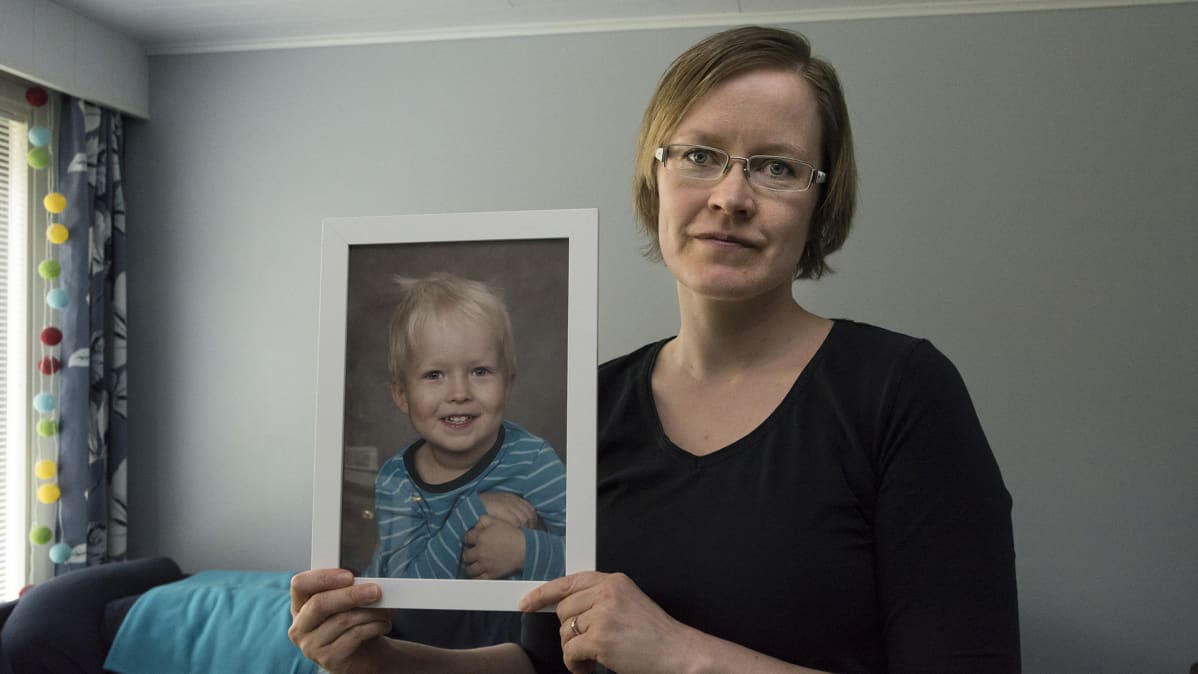 Anne Heikkinen pitää käsissään lapsensa valokuvaa.