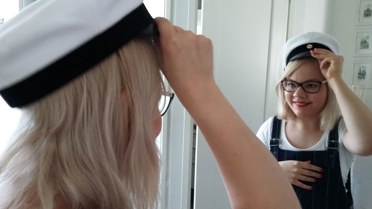 Elina Tytärniemi kokeilee valkolakkia päähänsä peilin edessä.