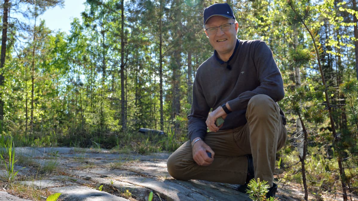 Kiviharrastaja Jorma Niemi metsässä kallion päällä.