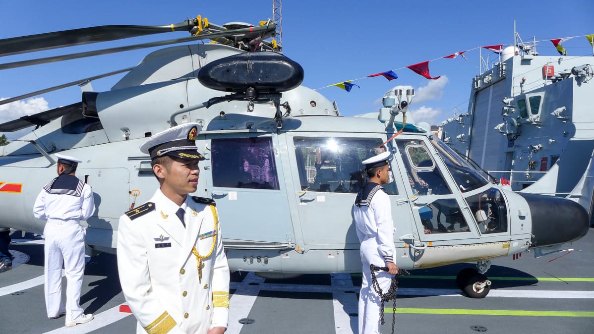 helikopteri ja kolme sotilasta laivan kannella