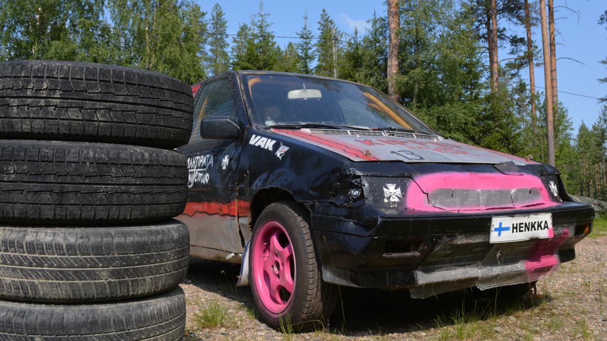 Hiukan romuttunut jokkisauto autonrengaiden vieressä. Taustalla mäntymetsää.