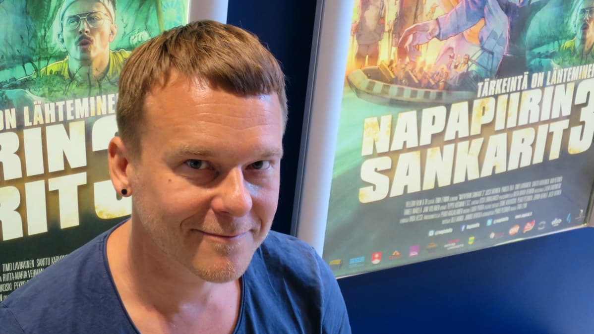 Mies elokuvajulisteiden keskellä katsoo kameraan
