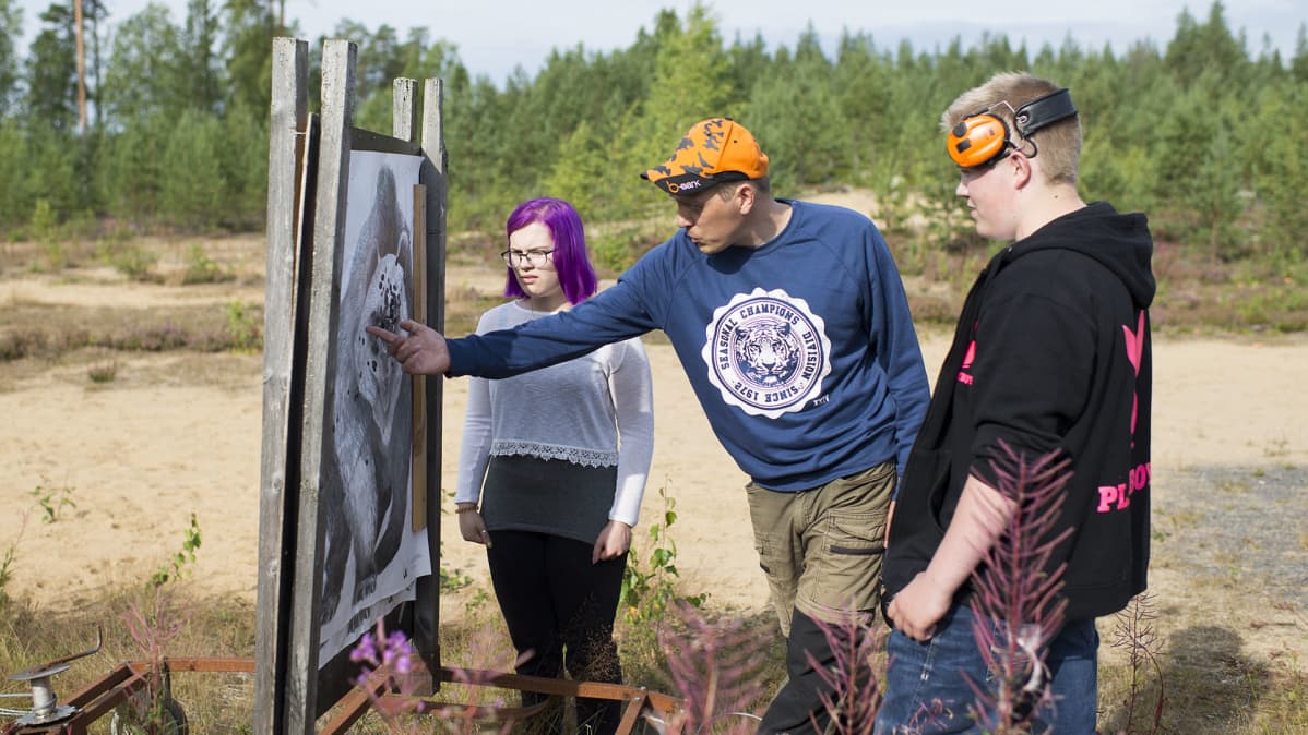 Ihmisiä ampumaradalla tarkastelemassa maalitaulua