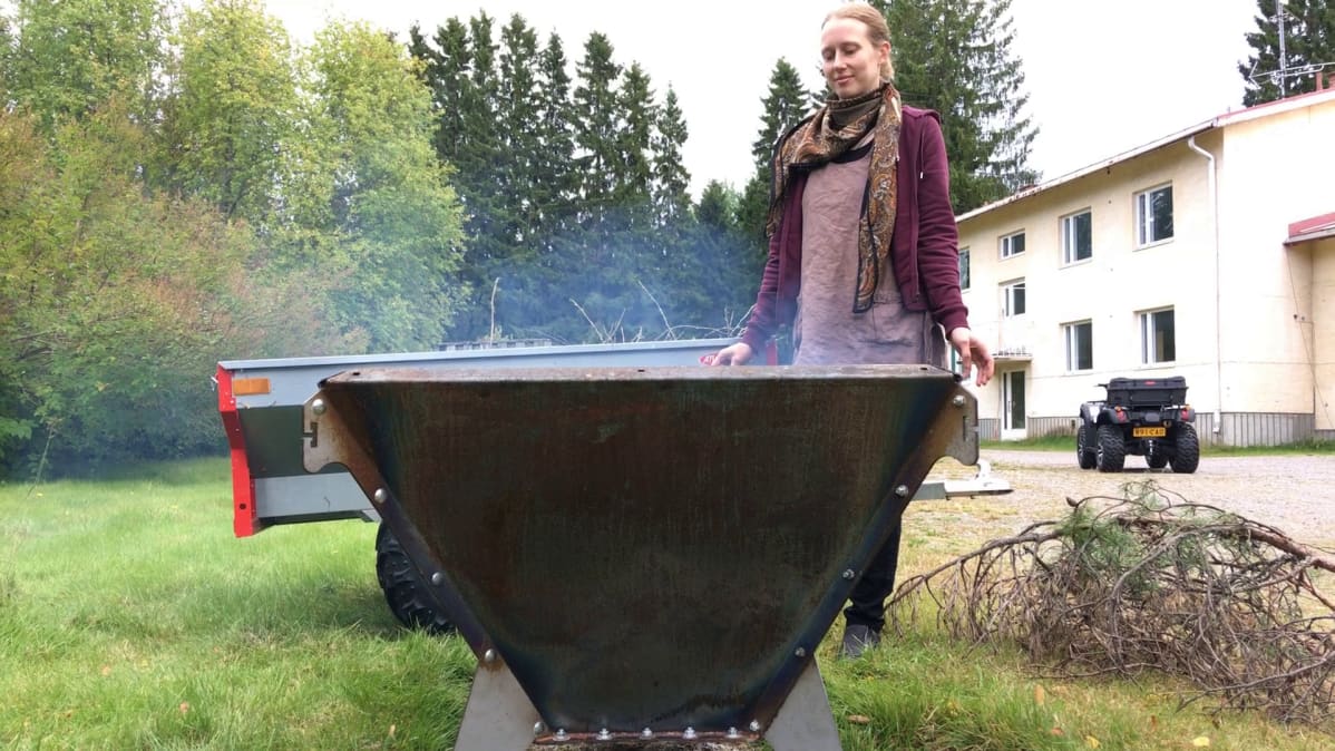 Nainen seuraa biohiilen syntyä hiilettimessä