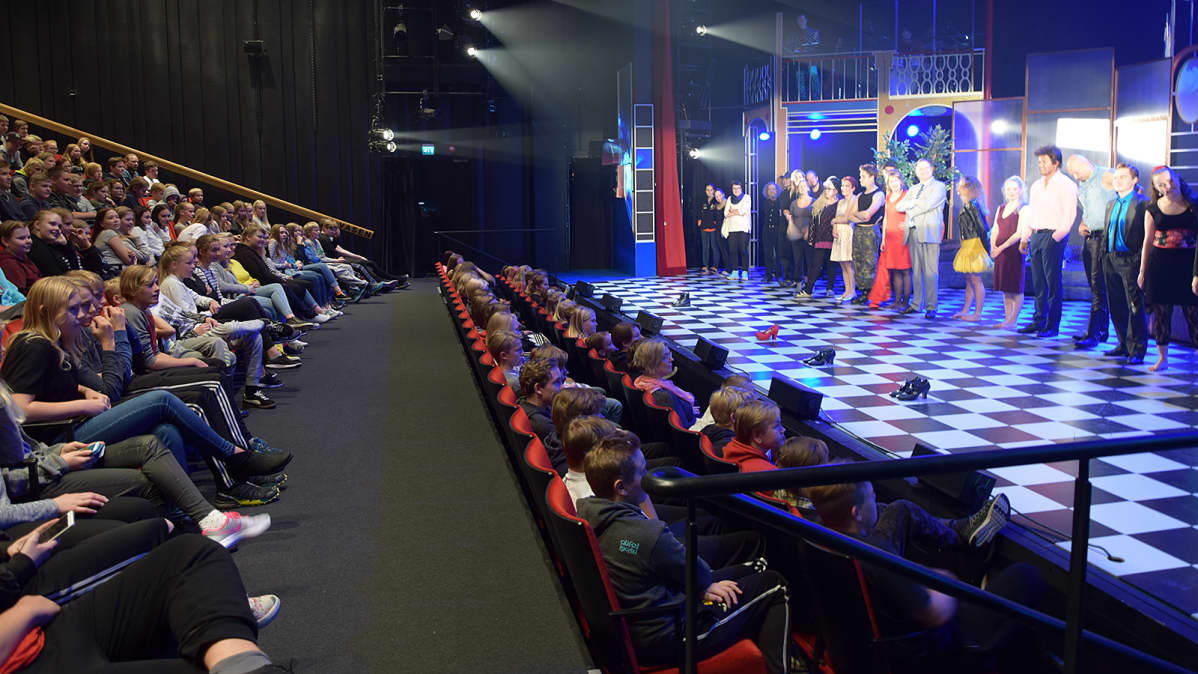 Taidetestaajanuoret teatterin katsomossa ja näyttelijät rivissä näyttämöllä
