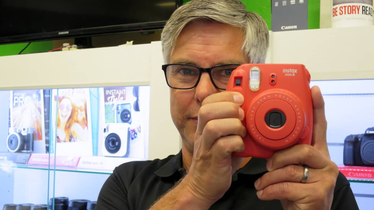 Mies katsoo kameraan kädessään instaxpikakuvakamera