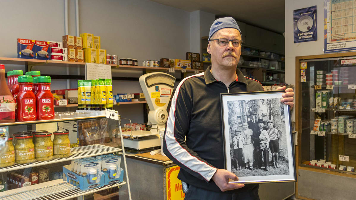Kauppias Ari Heikkinen näyttää valokuvaa perheestään.