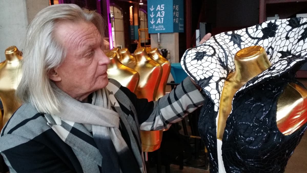 Jukka Rintala valmistelee punaiselle matolle pukunäyttelyä.