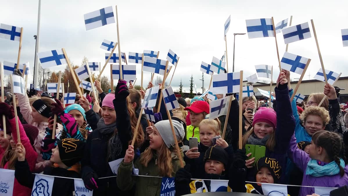 Lapset heiluttavat Suomen lippuja.