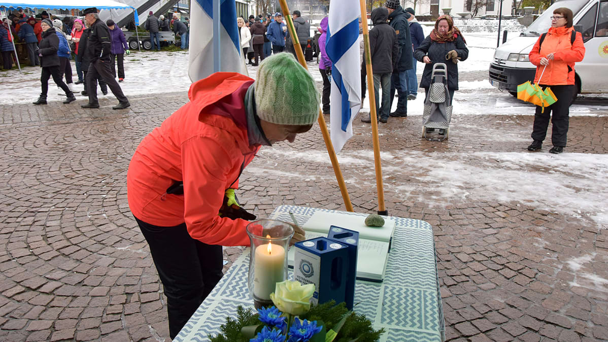 Nainen kirjoittaa nimensä kirjaan torilla