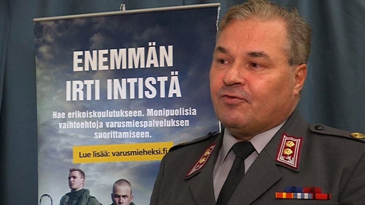 Everstiluutnatti seisoo Enemmän irti intistä-taulun vieressä