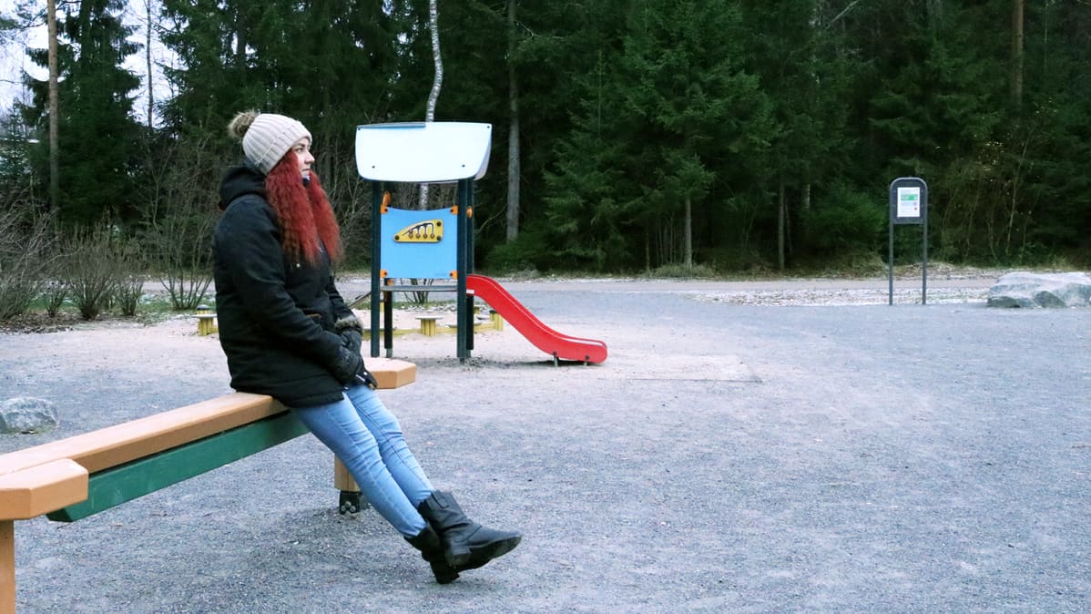 Nuori nainen istuu puistossa.