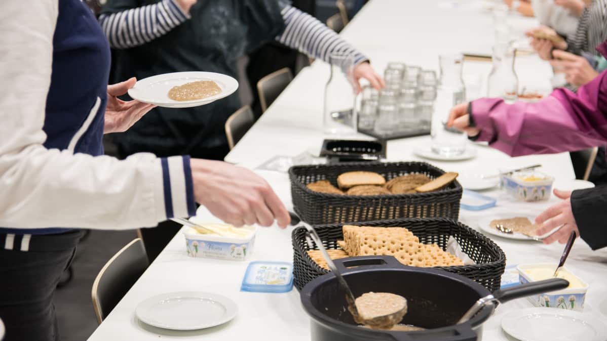 Ihmiset ottavat puuroa kattilasta.