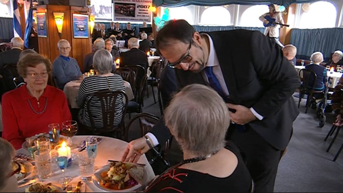 ruuan tarjoilua ravintolassa sotaveteraaneille, taustalla kuoro laulamassa , ravintola Pyöreä Torppa, Kouvola, yrittäjä Bekim Canhasi