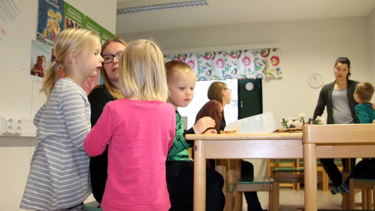 Yksinhuoltajien olkkari. Lapset ja äidit nauttivat välipalaa