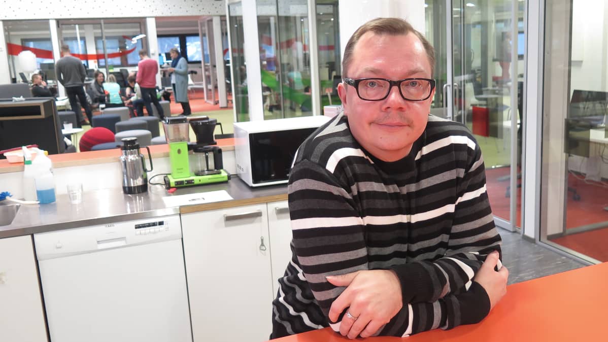 Mies nojaa keittiön pöytään Yle Tampereen toimituksessa