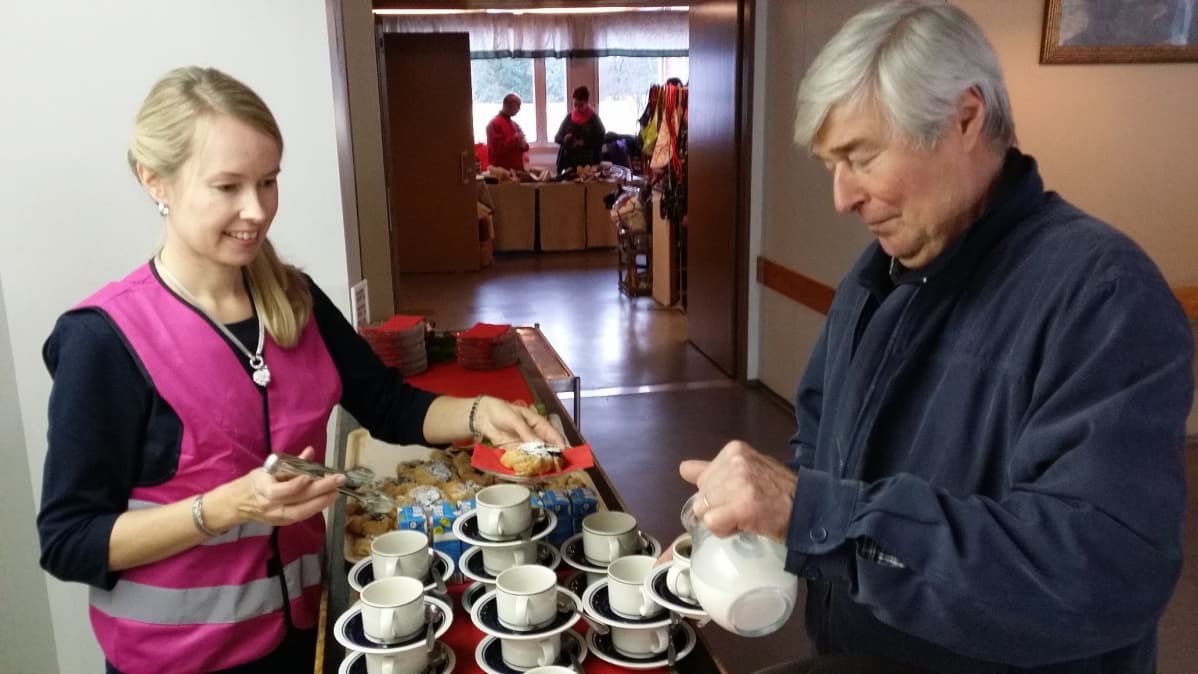 Nainen antaa joulutorttua asiakkaalle kahvilassa.
