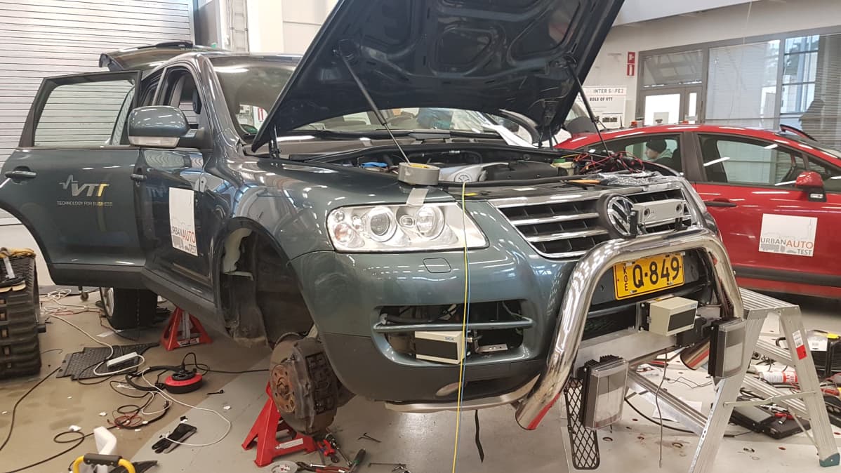 Robottiauto konepelti auki ja nostopalojen päällä hallissa