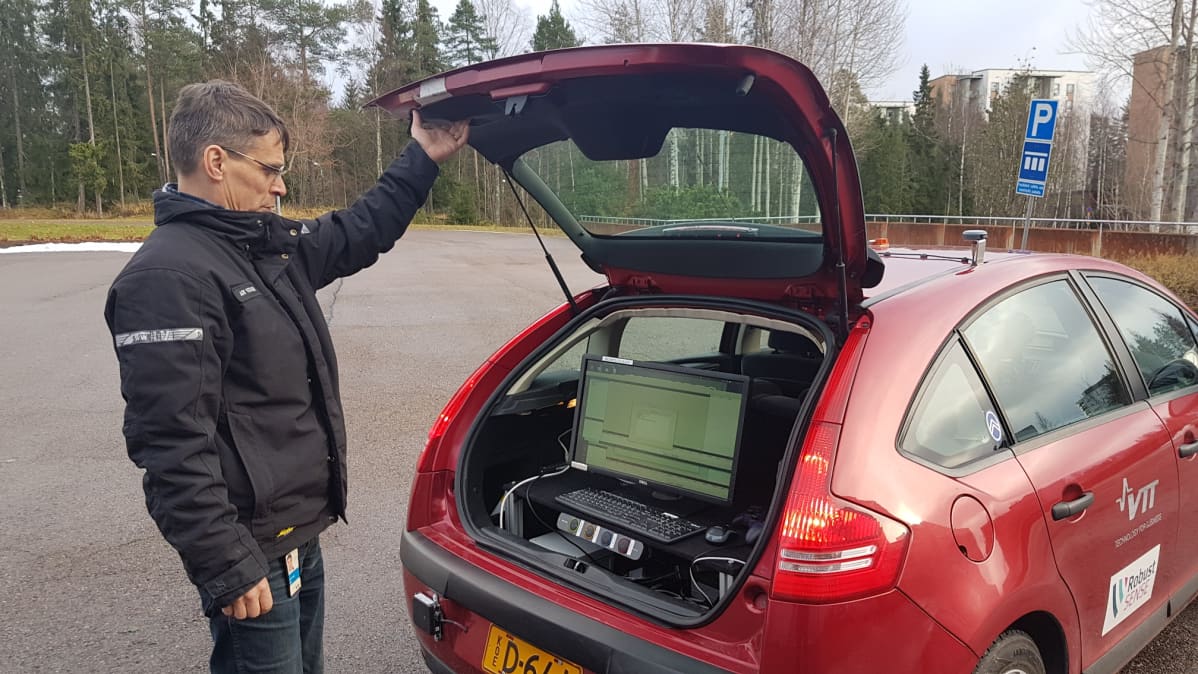 Mies näyttää auton takatilassa olevaa tietokonetta
