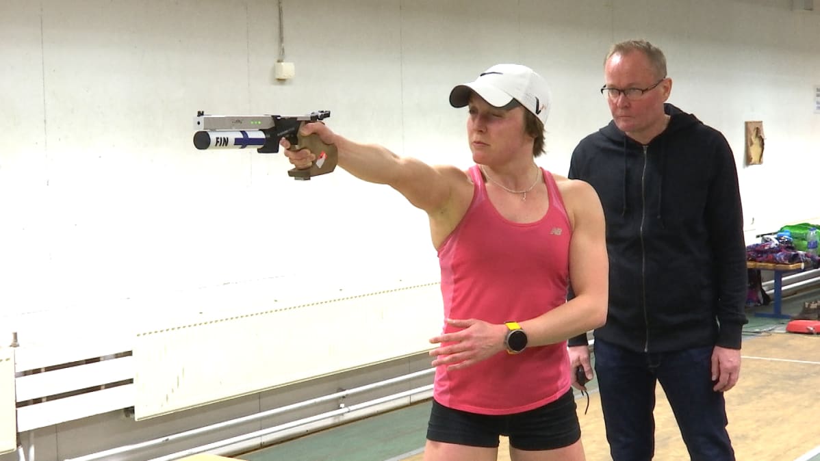 Eevi Bengs skjuter med laserpistol under Jouko Pakarinens övervakning.