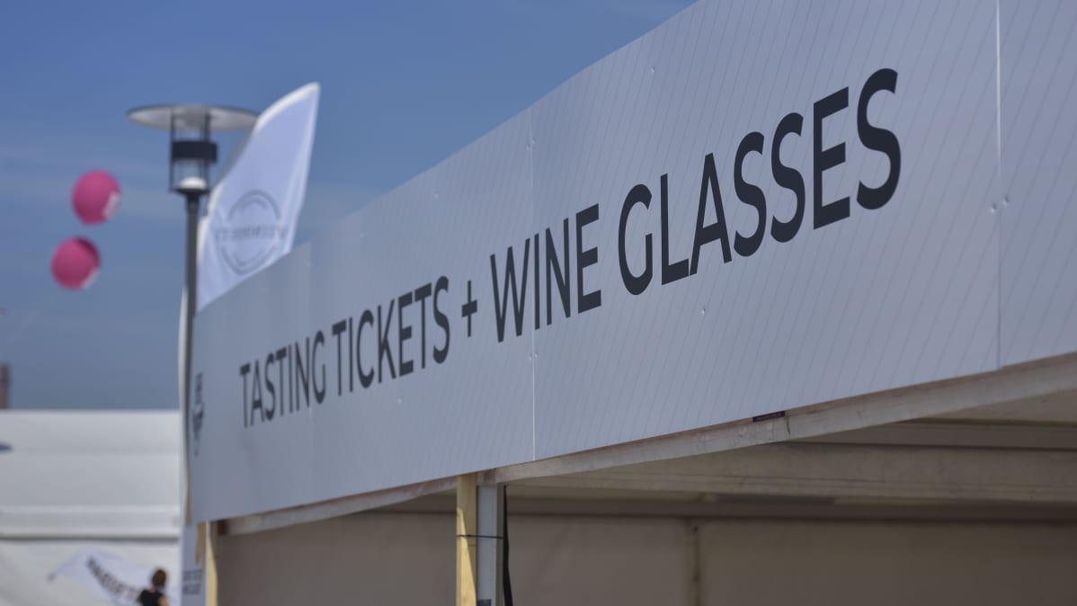 en skylt med texten tasting tickets and wine glasses på ett festivalområde