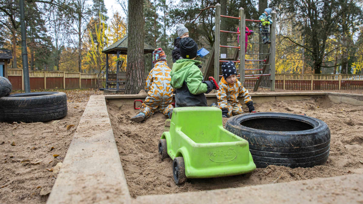 Lapsia leikkimässä hiekkalaatikolla.