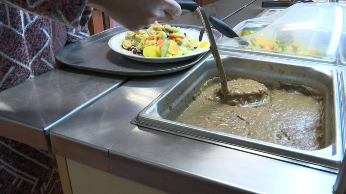 Naudanlihakastiketta otetaan lautaselle kauhalla koulun ruokalassa.