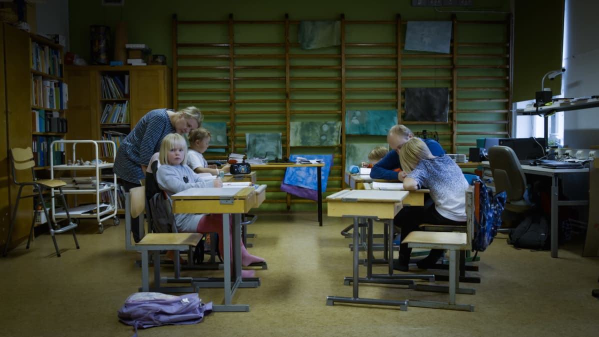 Utön alakoulussa on meneillään oppitunti. Lapset istuvat pulpeteissaan ja opettajat neuvovat tehtävissä,