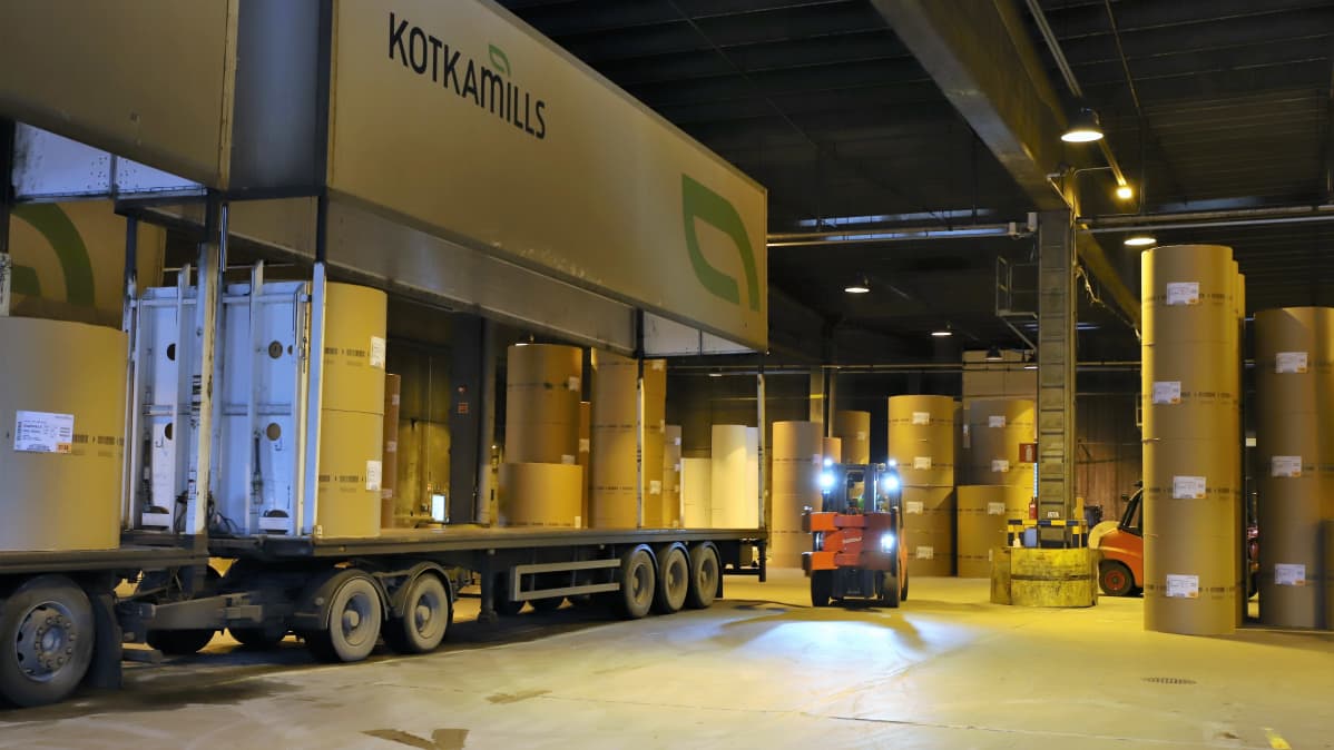 Trukki lastaa kartonkirullia rekka-autoon tehtaalla