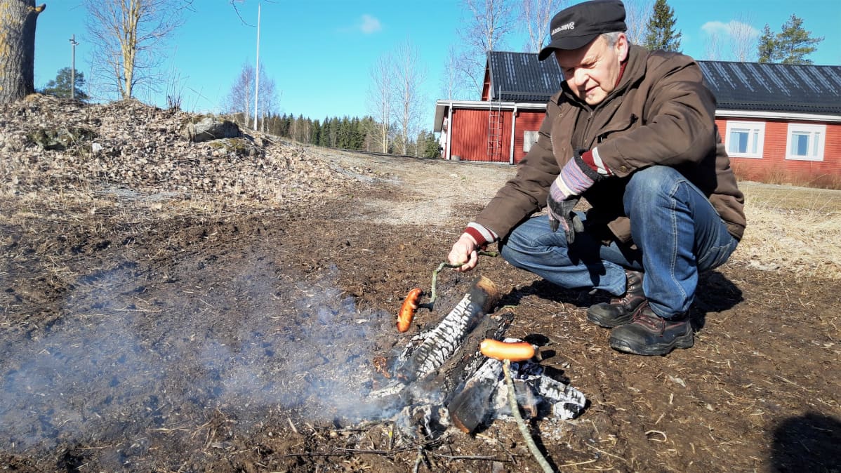 Mauri Laitila paistaa makkaraa nuotiolla Keskikylän nuorisoseuran pihalla