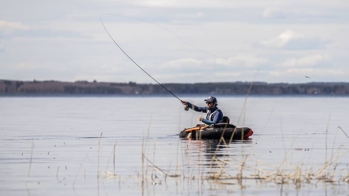 Mies virvelöi kelluntarenkaan päältä järven rannassa.