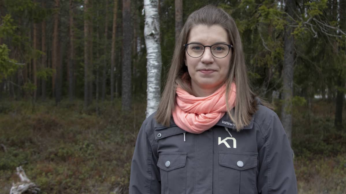 Terhi Ala-Hulkko. katsoo kameraan metsää taustalla