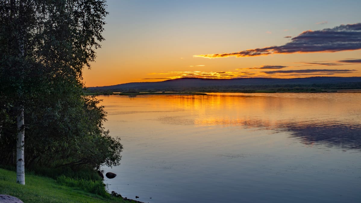 Maisema Ounas- ja Kemijokien risteykseen Rovaniemellä, keskiyön aurinko paistaa.
