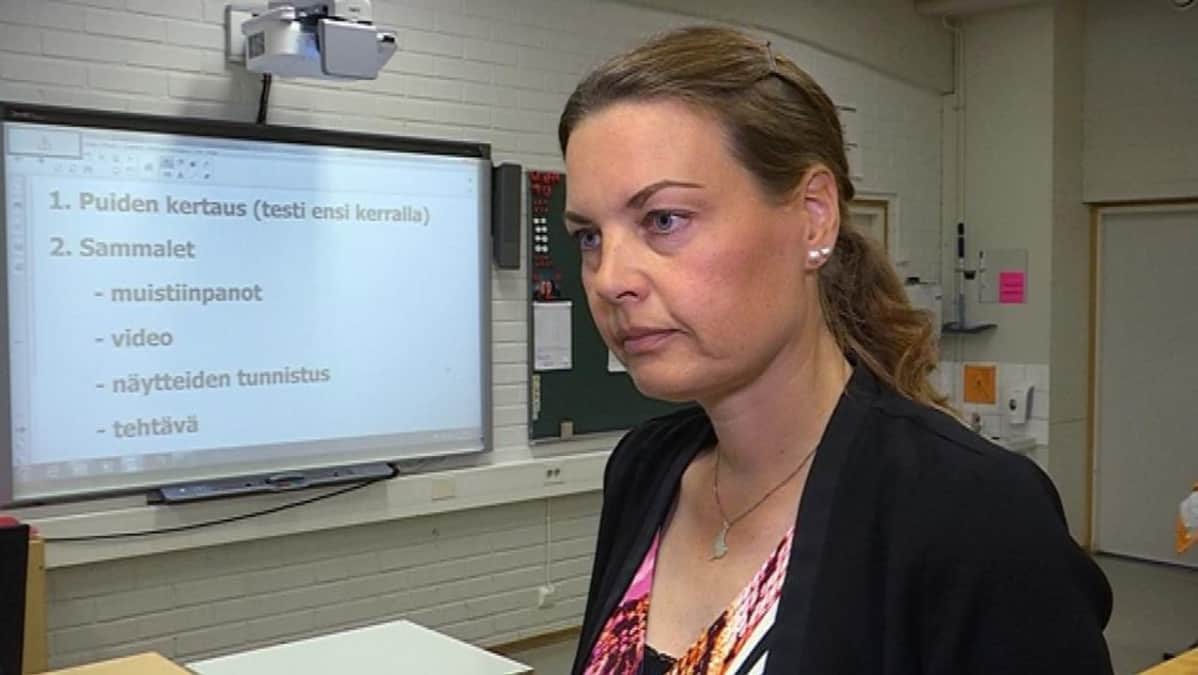 Naisopettaja suuren tietokonenäytön edessä