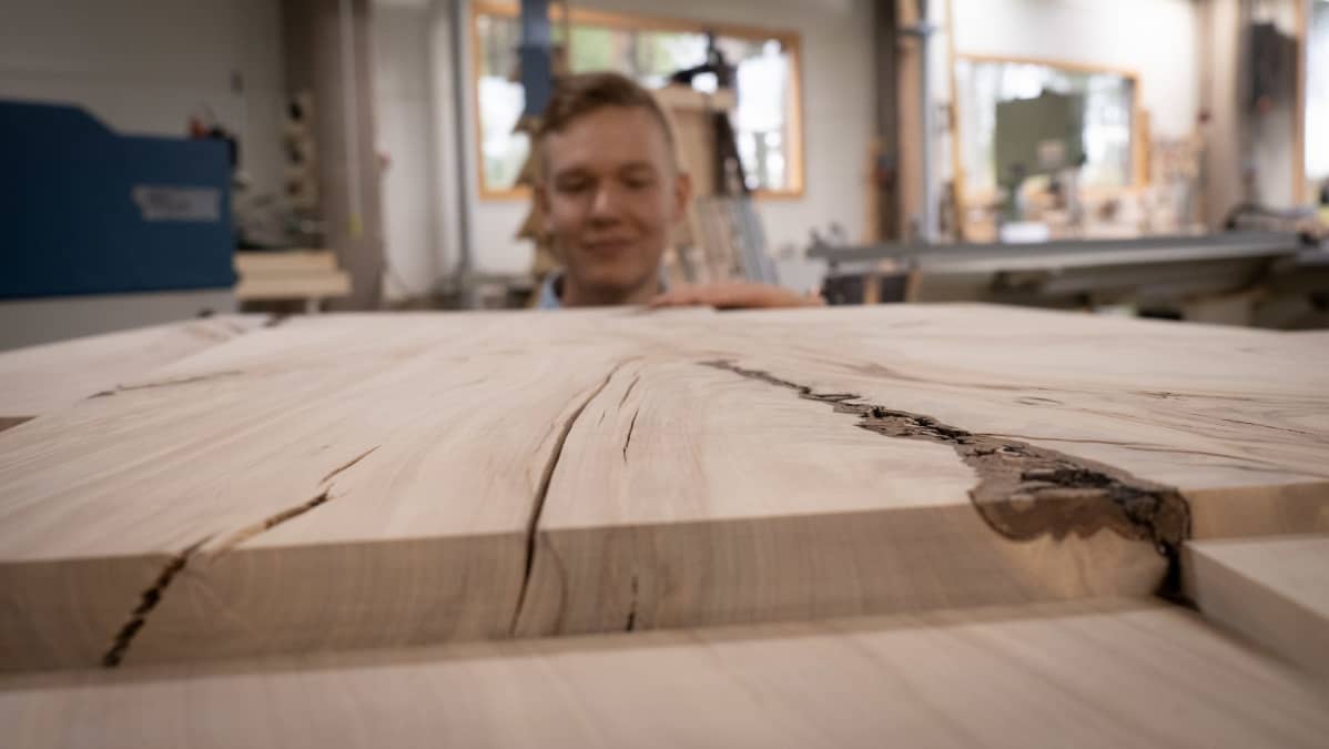 Mies tunnustelee kädellä höylättyä puupintaa