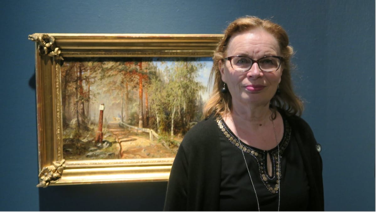 Nainen seisoo hämäläistä hiekkatietä kuvaavan taulun edessä
