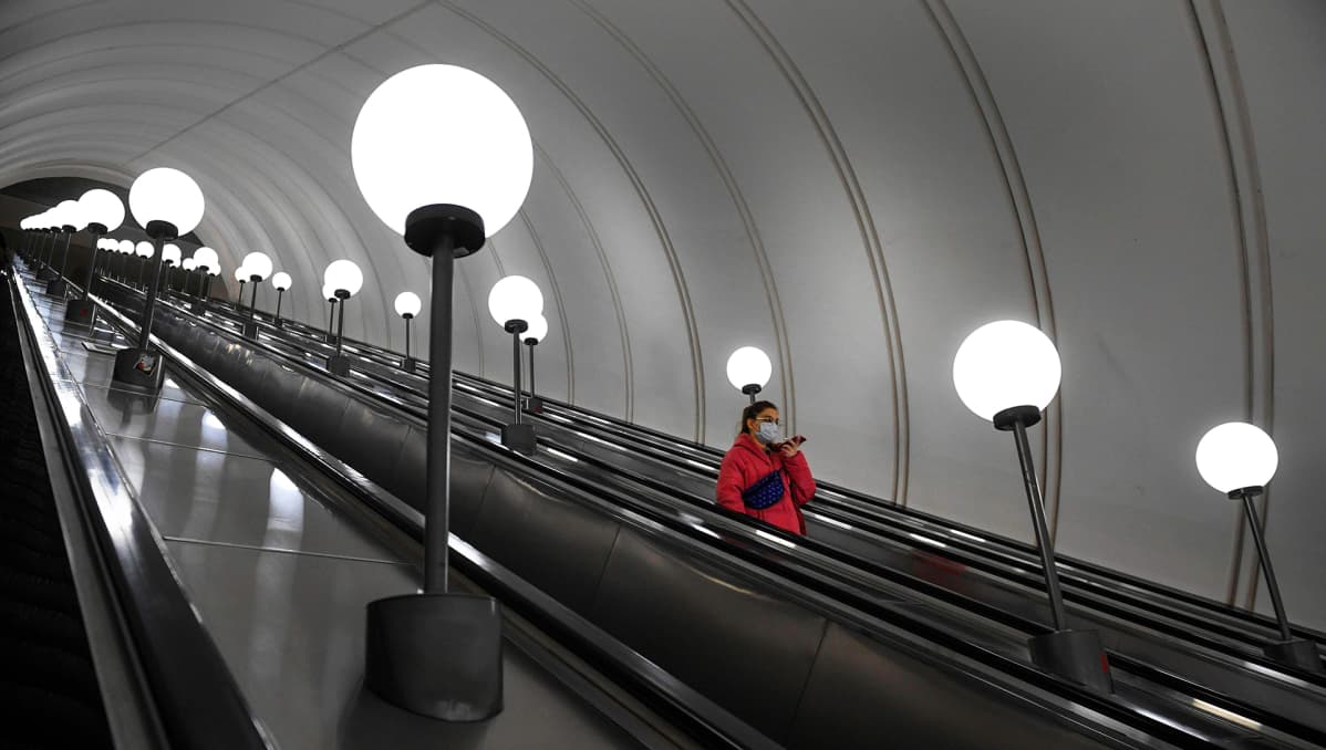 Yksinäinen matkustaja laskeutui liukuportaita asemalaiturille Moskovan metrossa.