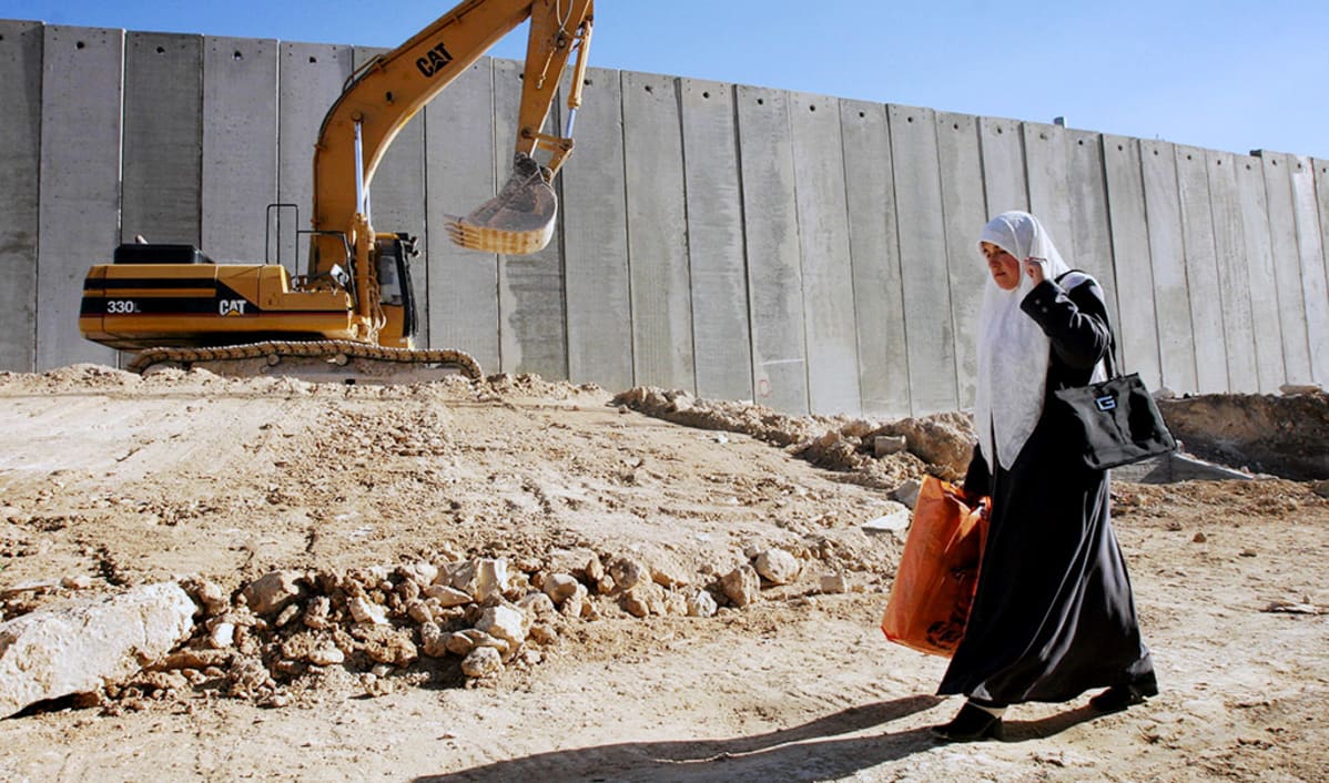 Palestiinalainen nainen kävelee israelilaisten rakentaman muurin vierustalla Itä-Jerusalemissa.